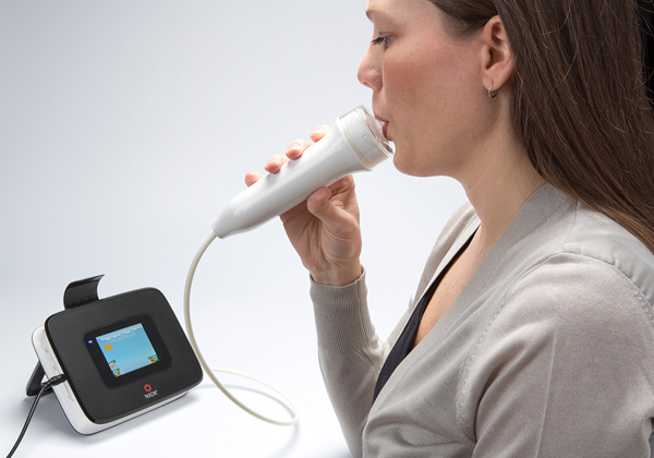 Woman using a device to test her exhaled nitric oxide